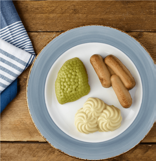 Image shows a high angle shot of a plate which has sausage, peas and mash on it.
